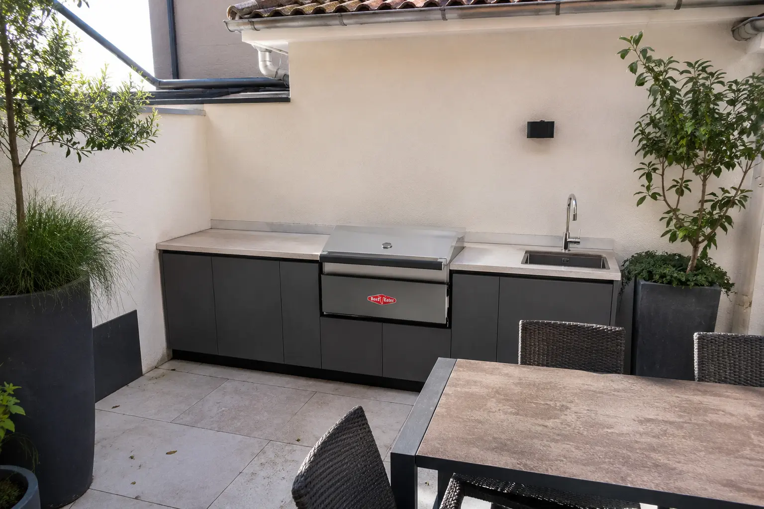 Einbaugrill als Herzstück einer mediterranen Outdoor-Küche bei Abendlicht