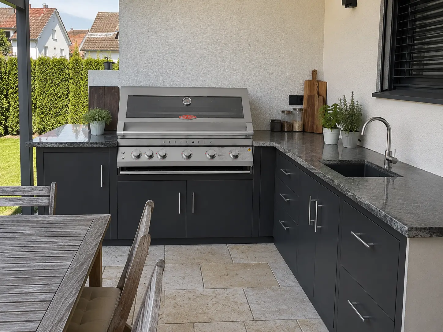 Einbaugrill in mediterraner Outdoor-Küche bei Abendsonne