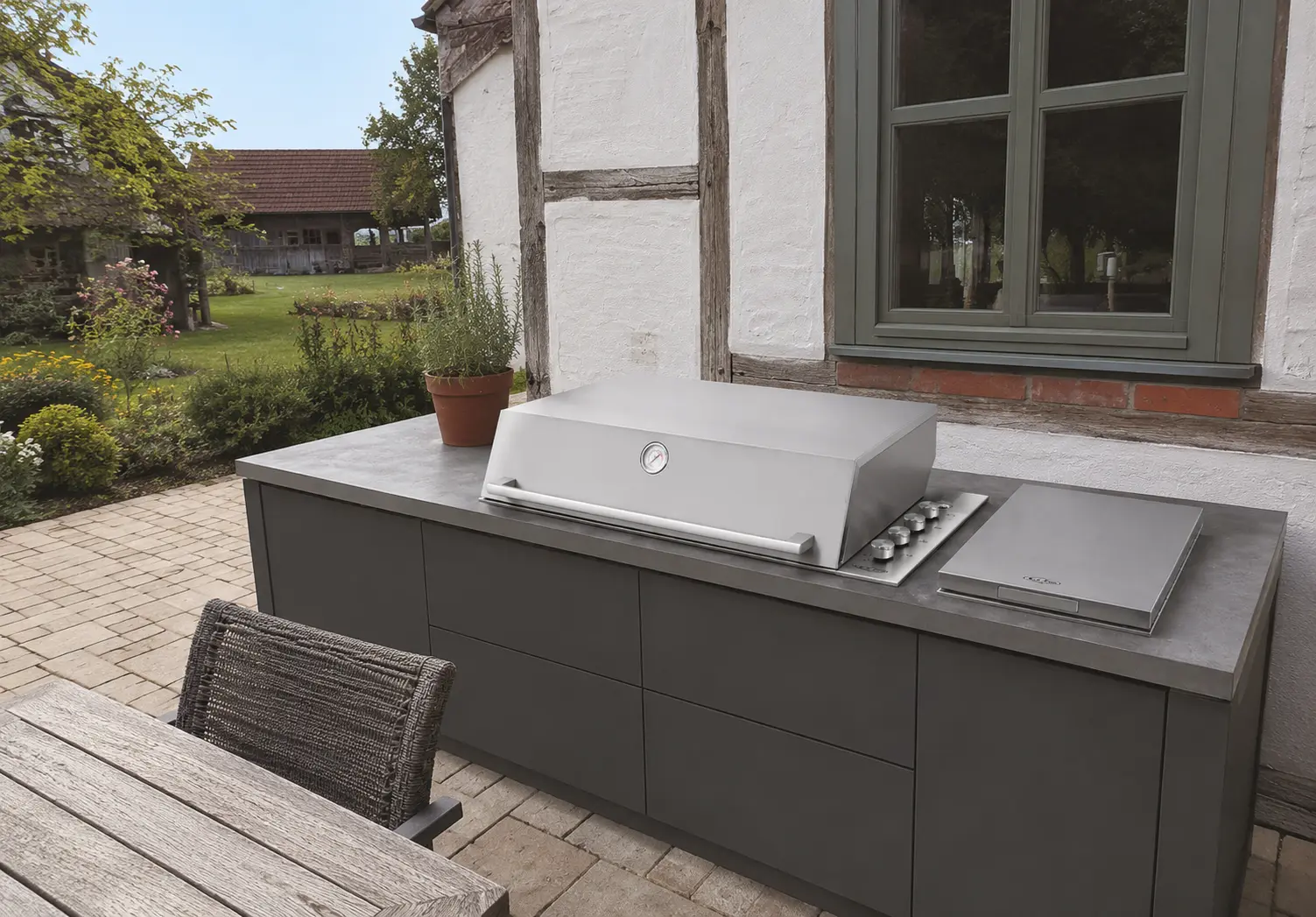 Einbaugrill in terracottafarbener Outdoor-Küche bei Abendsonne