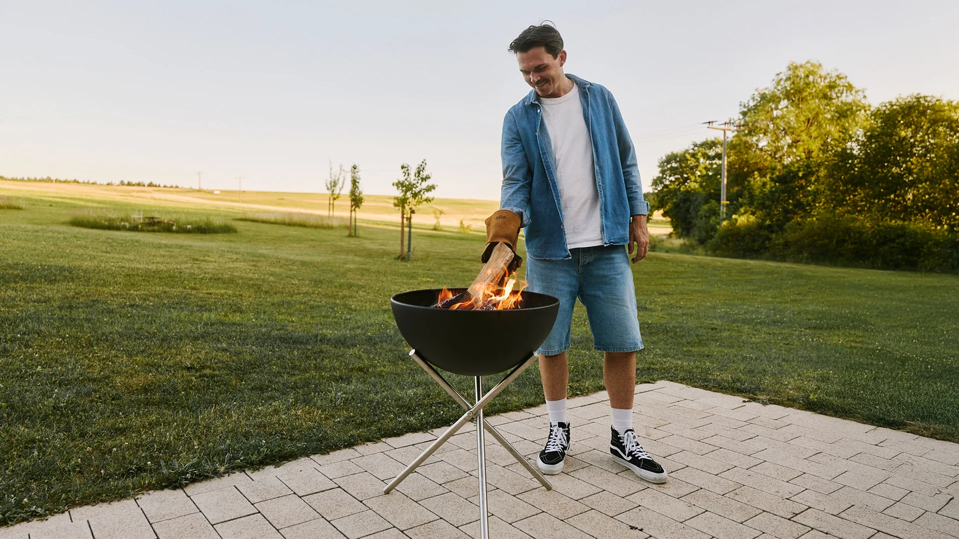 Feuerschale von Höfats mit brennendem Holz auf einer gepflasterten Terrasse im Garten